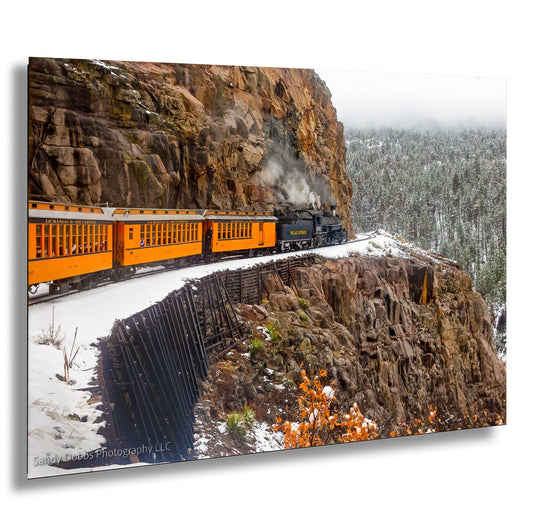 a train traveling down tracks next to a mountain