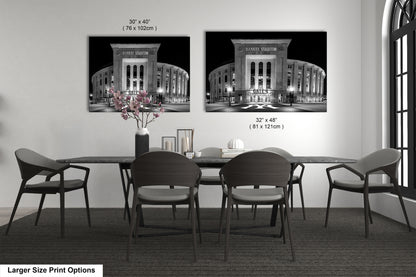 a dining room with a large dining table and chairs. There are two framed black and white photographs of Yankee Stadium hanging on the wall above the table.