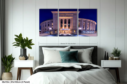 A bedroom with a large wall-mounted print of the Yankee Stadium at night, featuring the stadium's exterior and surrounding area.