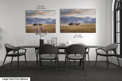 a dining room table with four chairs and two pictures on the wall