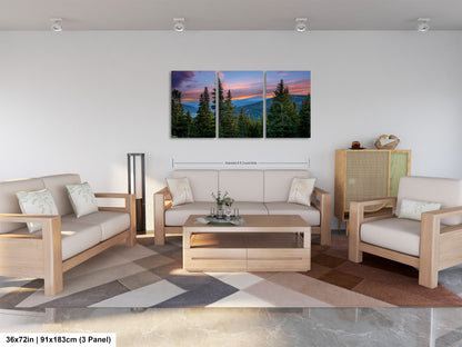 A modern living room with a large, three-panel landscape painting depicting a mountain range at sunset. The painting is hung on the wall above a wooden coffee table, which is surrounded by two white couches and a matching chair. The room has a minimalist and clean design, with a neutral color palette and a geometric patterned rug on the floor.