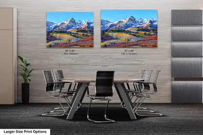 a dining room table with chairs and a painting of mountains