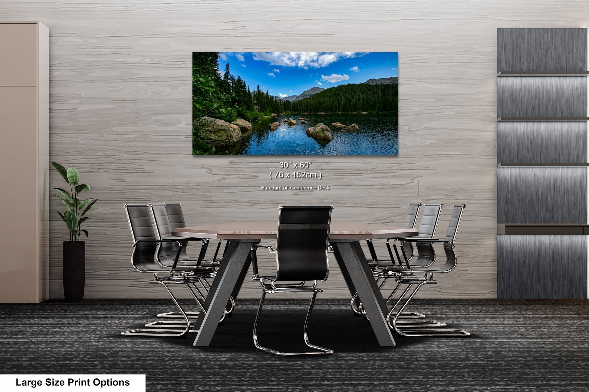 A modern office space with a large wall-mounted painting depicting a scenic lake surrounded by mountains. The painting is framed in a wooden frame and hangs above a wooden table with chairs.