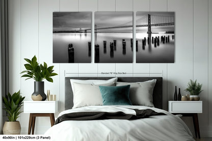 a black and white photo of a bed with a bridge in the background