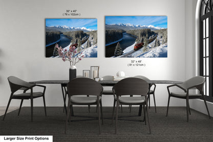 a dining room with a large dining table and six chairs. Two framed landscape photographs are displayed on the wall above the table, depicting snowy mountain scenery with a train passing through the landscape.