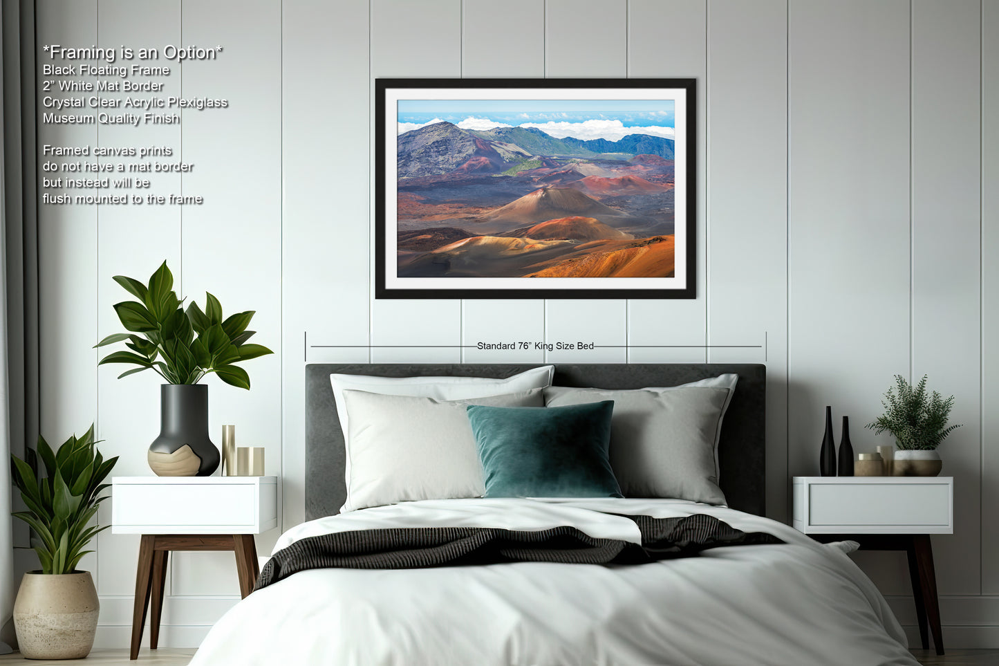 a bedroom with a large framed landscape painting hanging on the wall above a bed. The painting depicts a mountainous, desert-like scene with a clear blue sky and fluffy clouds. The room has a minimalist design with white walls, a gray headboard, and a black and white color scheme. There are also two nightstands with plants and decorative items, and a vase on one of the nightstands.