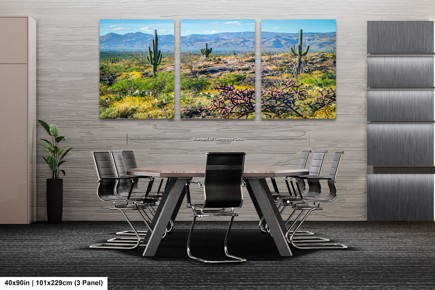 The image is a modern office space with a large, three-panel landscape painting depicting a desert scene with cacti and mountains in the background. The painting is mounted on the wall above a wooden table surrounded by chairs.