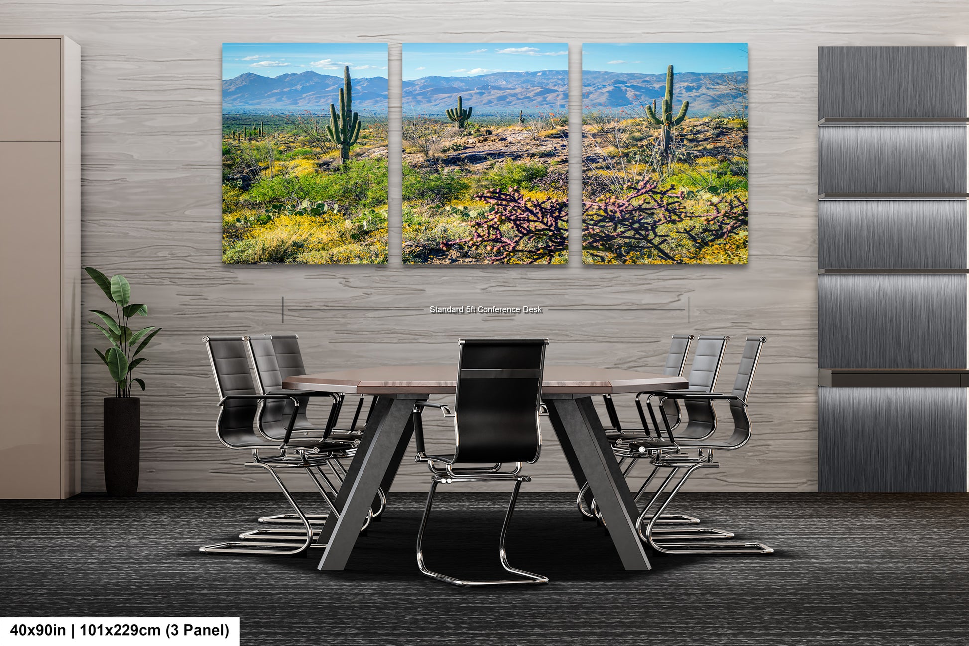 The image is a modern office space with a large, three-panel landscape painting depicting a desert scene with cacti and mountains in the background. The painting is mounted on the wall above a wooden table surrounded by chairs.