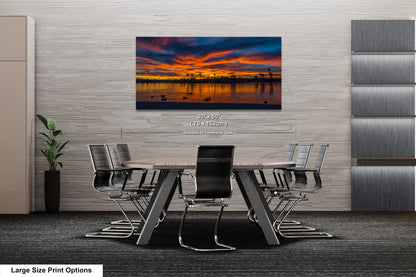 a modern office space with a large, colorful sunset painting hanging on the wall above a conference table surrounded by chairs.