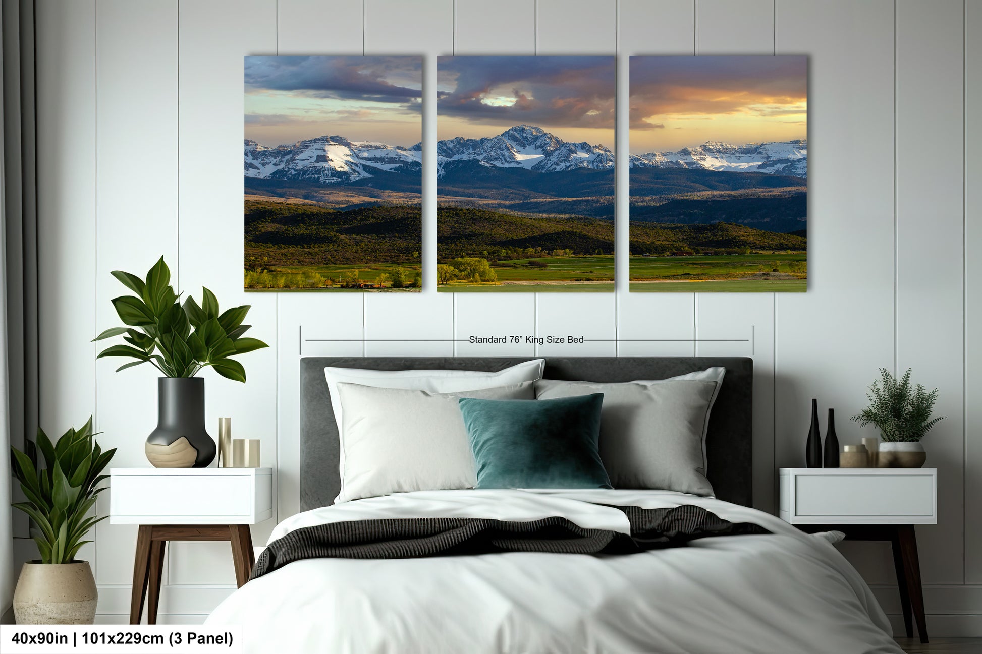 The image is a bedroom with a large, three-panel landscape painting hanging on the wall above the bed. The painting depicts a scenic mountain range with a cloudy sky, creating a serene and picturesque atmosphere.