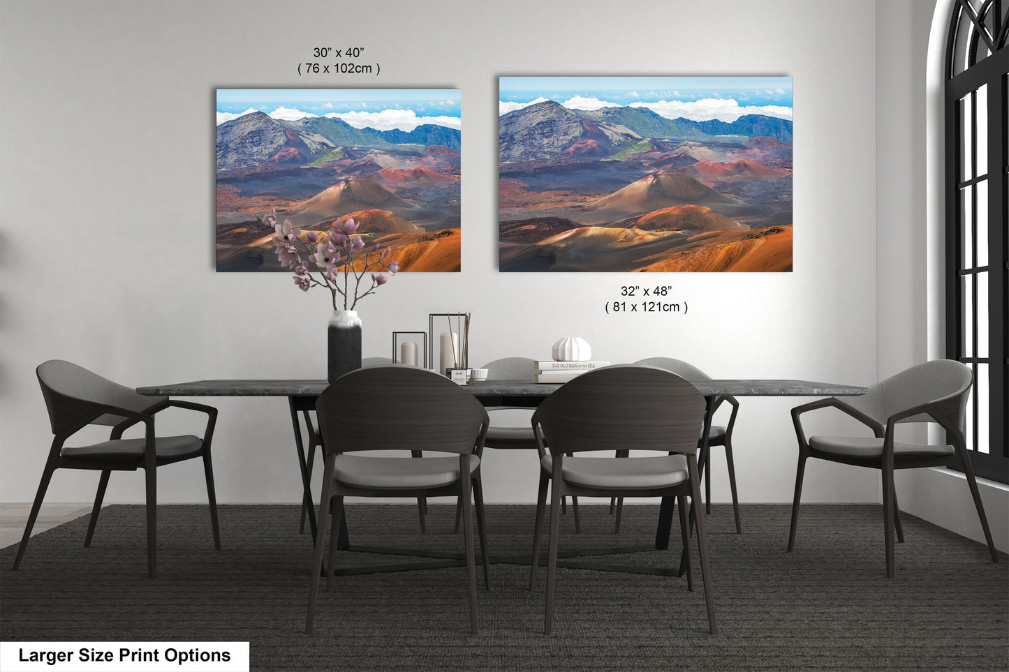 two large landscape paintings hanging on a wall above a dining table with chairs.