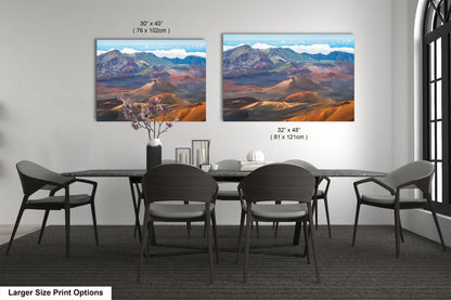 two large landscape paintings hanging on a wall above a dining table with chairs.