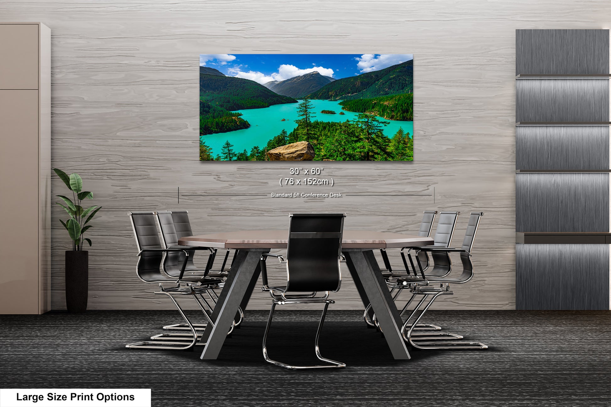 A large-sized print of a scenic mountain landscape with turquoise waters is displayed on the wall of a modern office space.