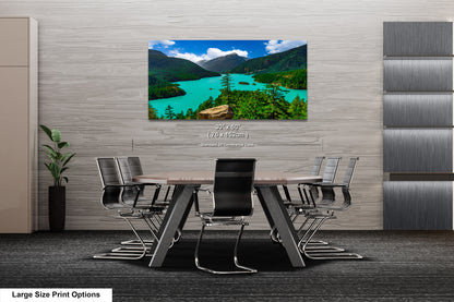 A large-sized print of a scenic mountain landscape with turquoise waters is displayed on the wall of a modern office space.
