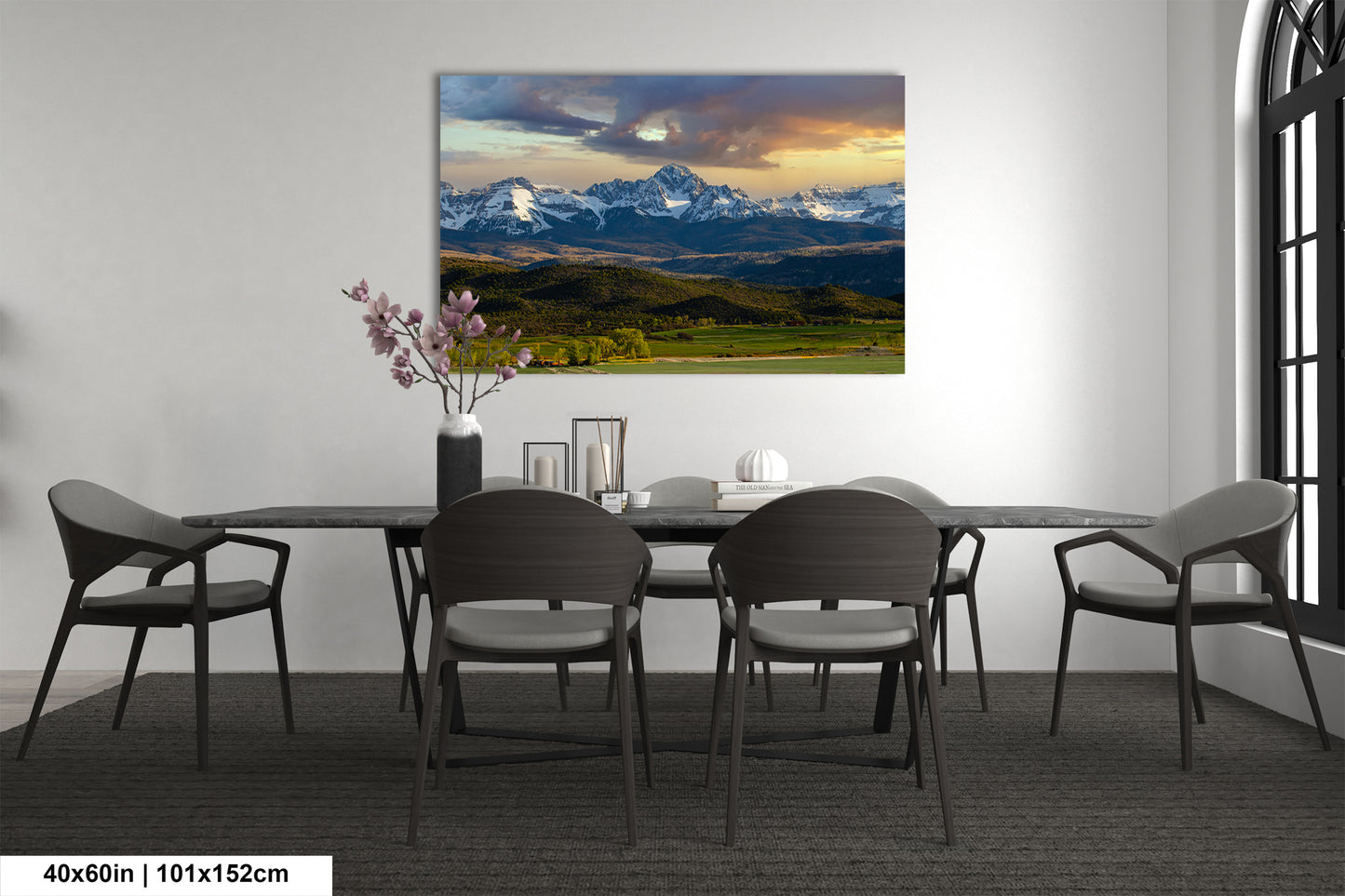 a dining room with a large landscape painting hanging on the wall above a wooden table surrounded by chairs.