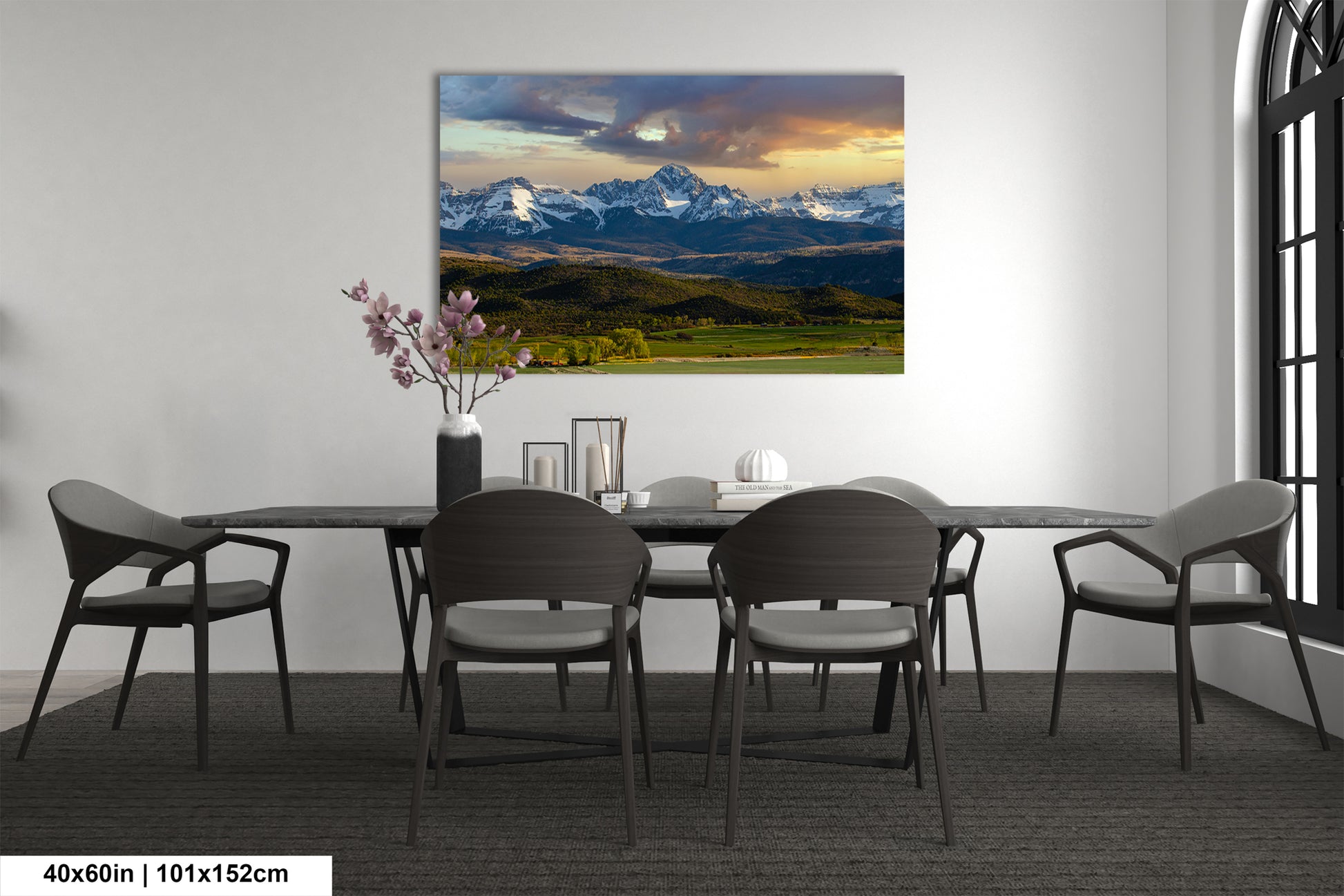 a dining room with a large landscape painting hanging on the wall above a wooden table surrounded by chairs.