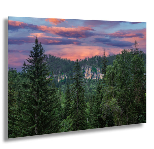a sunset view of a forest with a mountain in the background