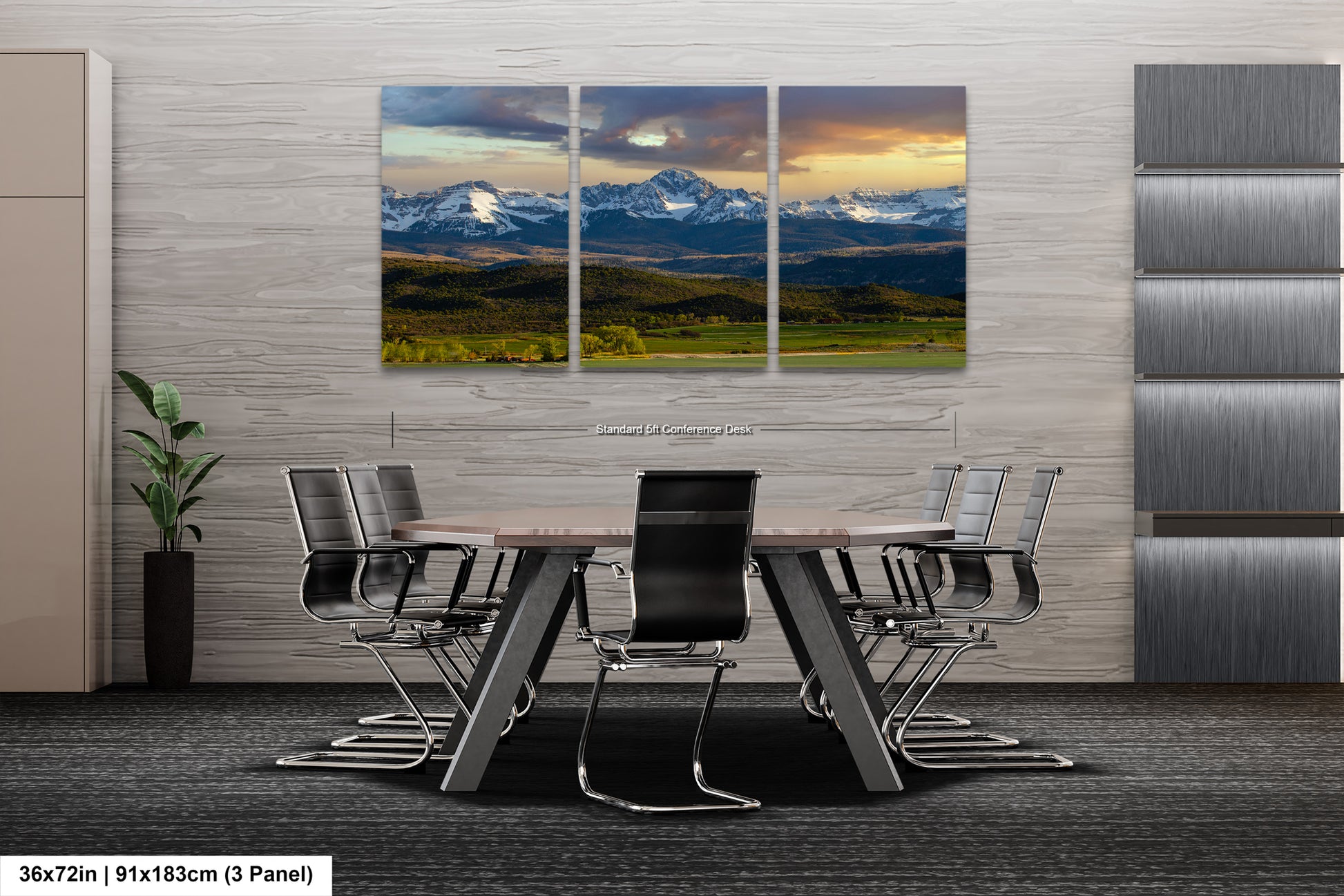 A modern office space with a large, three-panel landscape painting of a mountain range hanging on the wall. The painting features a dramatic sky with clouds and a valley below. The office has a sleek, minimalist design with gray walls and a gray carpeted floor. The room is furnished with a large wooden table surrounded by black chairs.