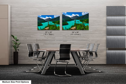 a modern office space with a large wooden table surrounded by black chairs. Above the table, there are two framed landscape photographs depicting a scenic mountain view with turquoise water. The photographs are labeled with their respective sizes, including 20 x 30" and 24 x 36" (61 x 91 mm) dimensions.