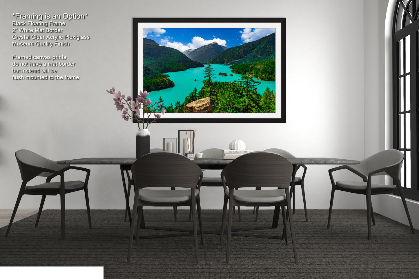 a modern dining room with a large framed landscape photograph hanging on the wall above a black dining table surrounded by six chairs. The photograph depicts a scenic mountain landscape with a turquoise lake and lush green forests.