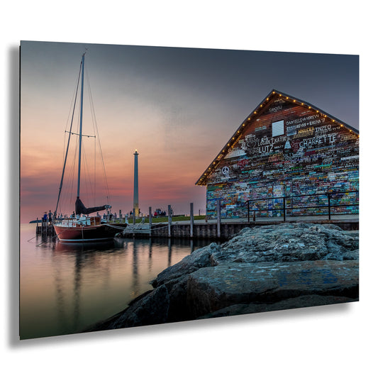 A colorful building with a sailboat docked in front of it, set against a backdrop of a sunset sky.