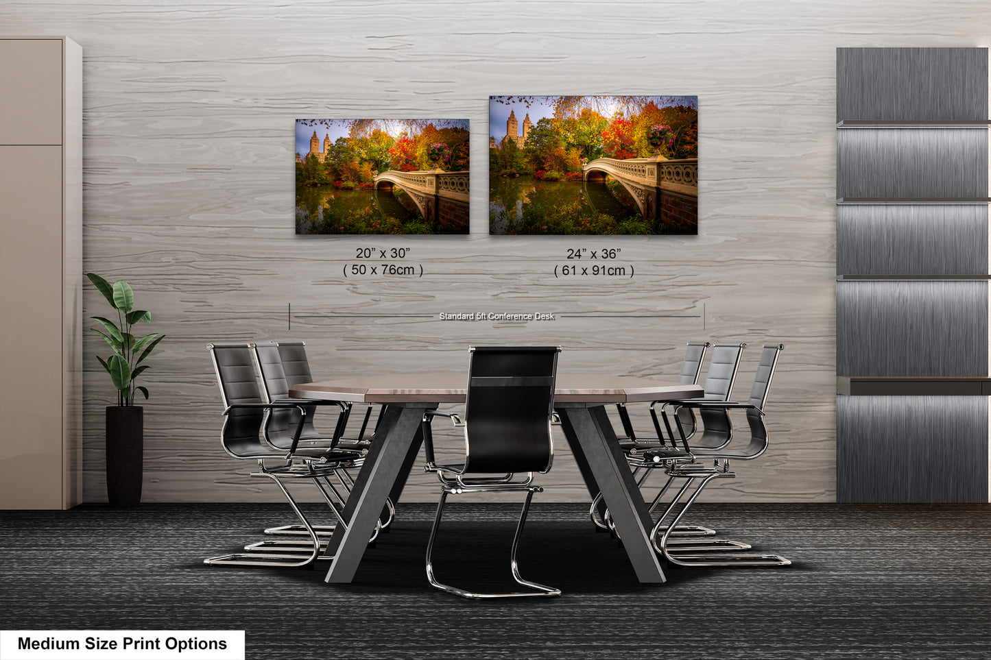 a modern office or conference room setting with a large wooden table surrounded by black chairs. Two framed landscape photographs are displayed on the wall above the table, depicting a scenic view of a bridge and trees. The photographs are of medium size, with dimensions of 20 x 30" and 24 x 36" (50 x 76" and 61 x 91" respectively).
