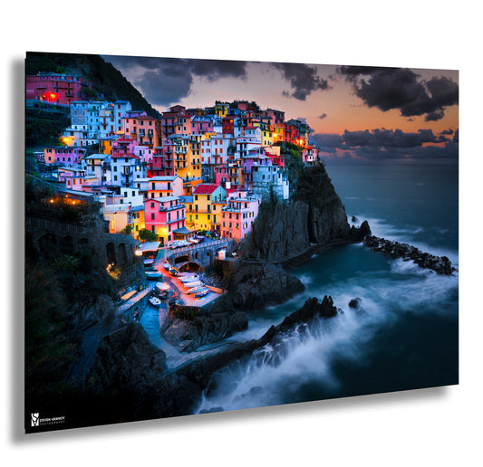 a picture of a village on a cliff by the ocean