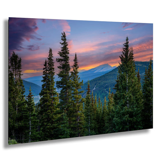 a serene mountain landscape at sunset, with a vibrant sky filled with colorful clouds and a majestic mountain range in the distance.