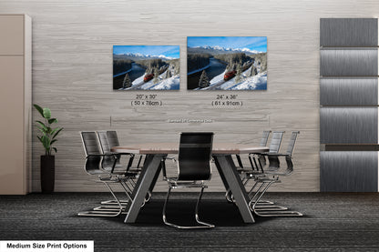a modern office space with a large wooden table surrounded by black chairs. Two framed landscape photographs are displayed on the wall above the table, depicting snowy mountain scenery. The text indicates that the medium size print options include the two framed photographs.