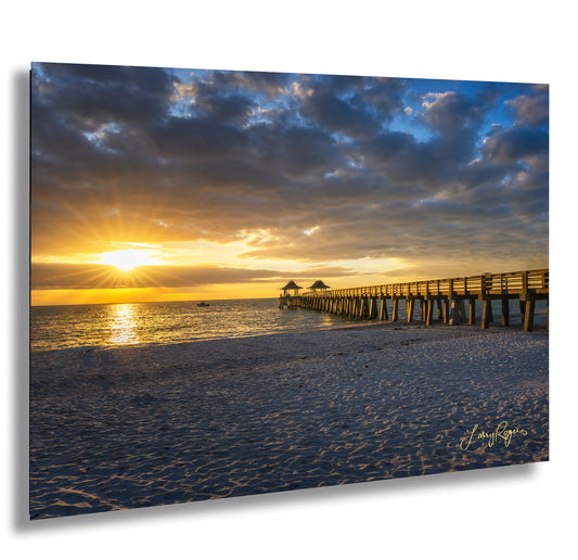 a pier on a beach with a sunset in the background