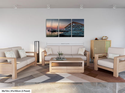 The image is a modern living room with a large wall art piece depicting a serene seascape at sunset. The room is furnished with a white sofa, a wooden coffee table, and a potted plant. The overall design and decor create a calm and inviting atmosphere.