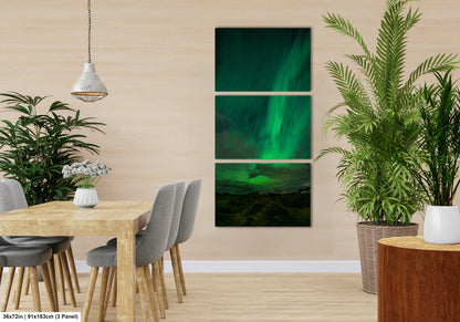 a modern dining room with a wooden table and chairs, a potted plant, and a hanging light fixture. The room has a neutral color scheme and features a large painting of the Aurora Borealis ( Aurora ) on the wall.