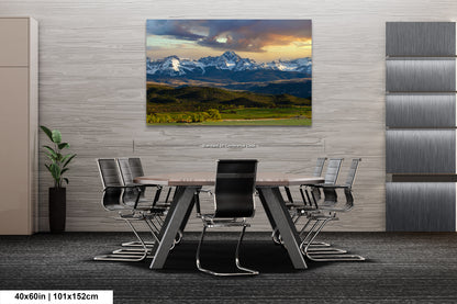 a modern office space with a large, framed landscape painting of a mountain range hanging on the wall above a conference table with chairs.
