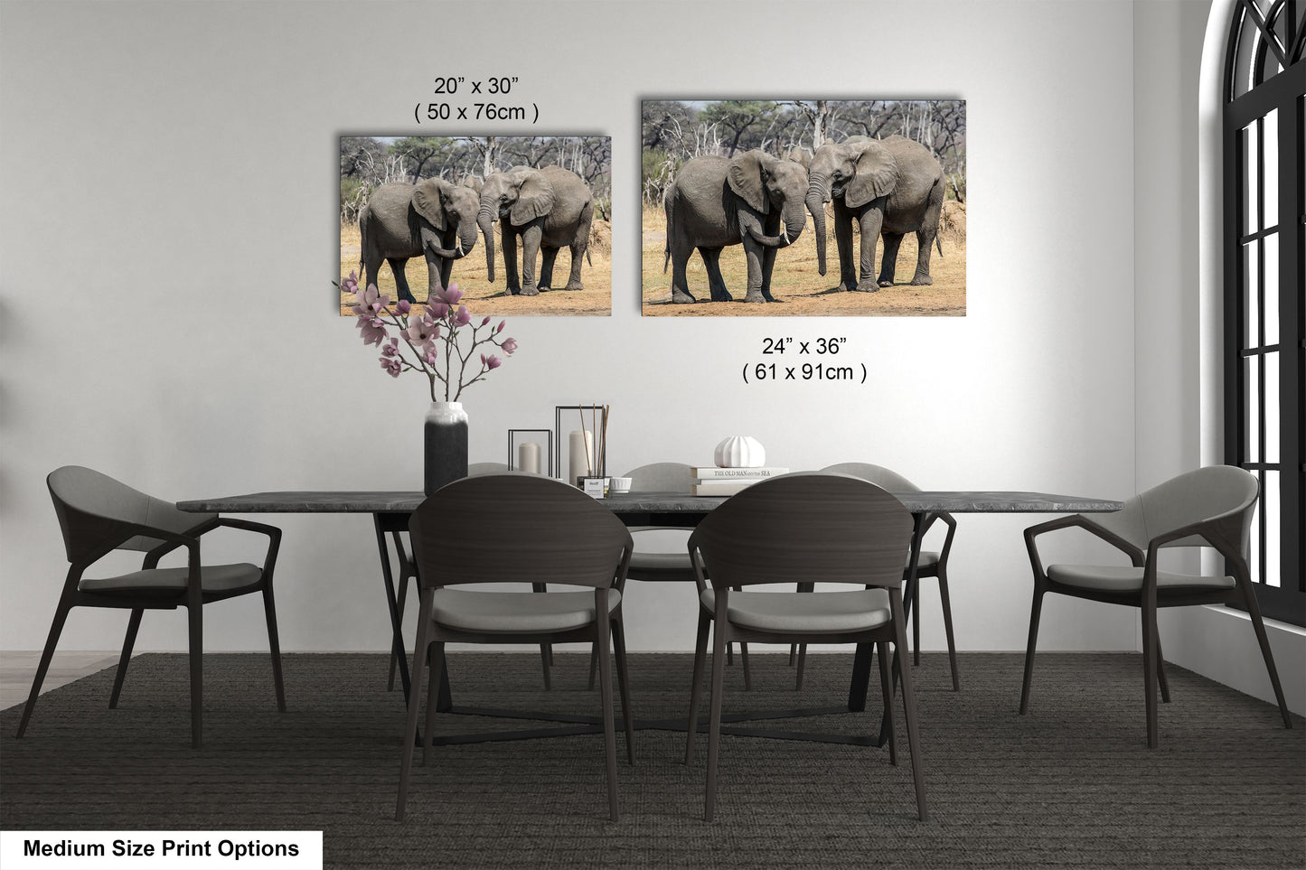 a dining room table with chairs and two pictures of elephants on the wall