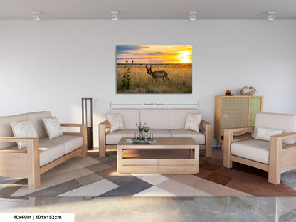 a serene living room with a large, vibrant painting of a sunset over a field hanging on the wall. The painting features a majestic antelope standing in the foreground, adding a touch of wildlife to the scene. The room is furnished with a sofa, two armchairs, and a coffee table, creating a cozy and inviting atmosphere. The overall layout and design of the room suggest a harmonious blend of nature and comfort.