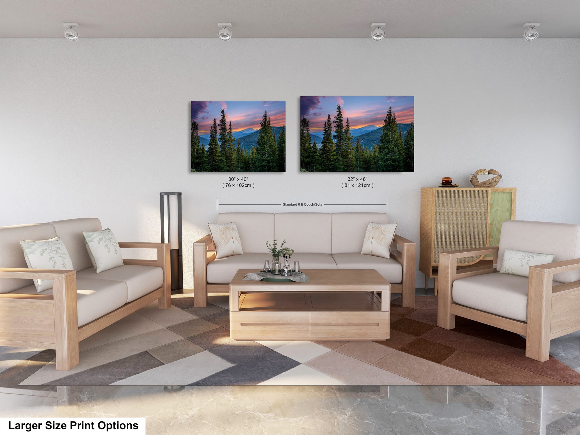 a modern living room with a large sofa, two chairs, and a coffee table. Above the furniture, there are two framed landscape paintings depicting a mountain scene with pine trees and a colorful sunset. The paintings are of similar size, and the text indicates that the larger size print options are available.