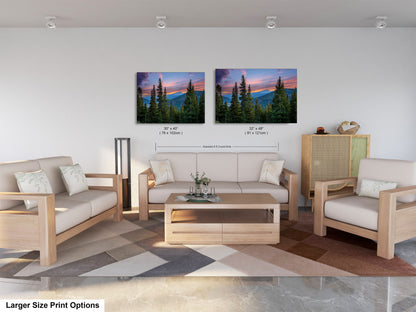 a modern living room with a large sofa, two chairs, and a coffee table. Above the furniture, there are two framed landscape paintings depicting a mountain scene with pine trees and a colorful sunset. The paintings are of similar size, and the text indicates that the larger size print options are available.