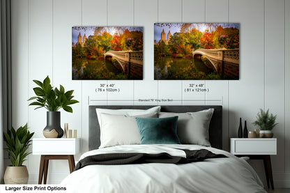 a bedroom with a bed and nightstands, along with two framed prints of a scenic landscape featuring a bridge and trees in autumn colors.