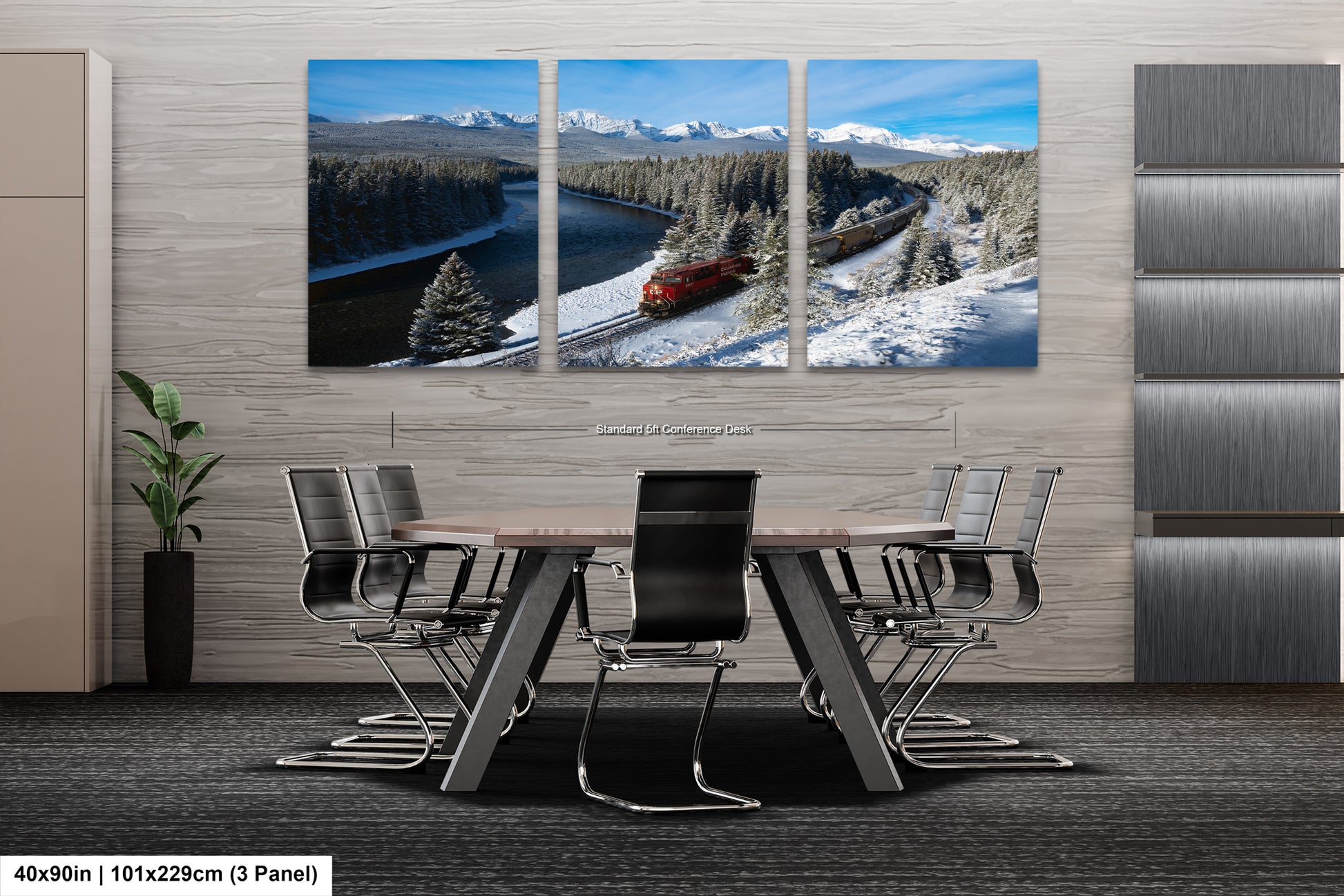 A modern office space with a large, three-panel landscape painting depicting a snowy mountain scene with a train passing through it. The painting is mounted on the wall above a wooden table surrounded by chairs.