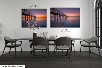 a dining room table with four chairs and two pictures on the wall