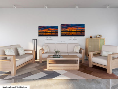 a modern living room with a white sofa, two chairs, and a coffee table. There are two framed landscape paintings on the wall above the seating area, depicting a sunset over a body of water. The room has a neutral color scheme with a geometric patterned rug on the floor.