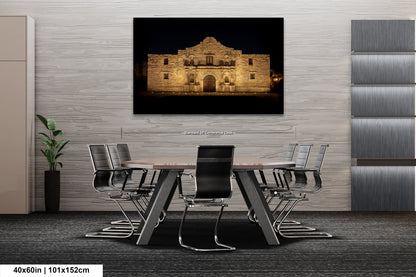 a modern office space with a large framed photograph of the Alamo in the background, mounted on the wall above a wooden table surrounded by chairs.