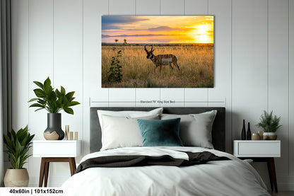 a serene bedroom scene with a large bed, nightstands, and a painting of a gazelle in a field at sunset.
