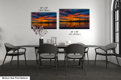a modern dining room with a large dining table and six chairs. Two large paintings of a sunset are displayed on the wall above the table, creating a serene and artistic atmosphere.