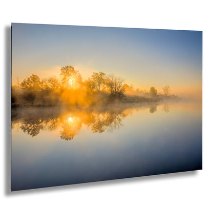the sun is setting on a foggy lake