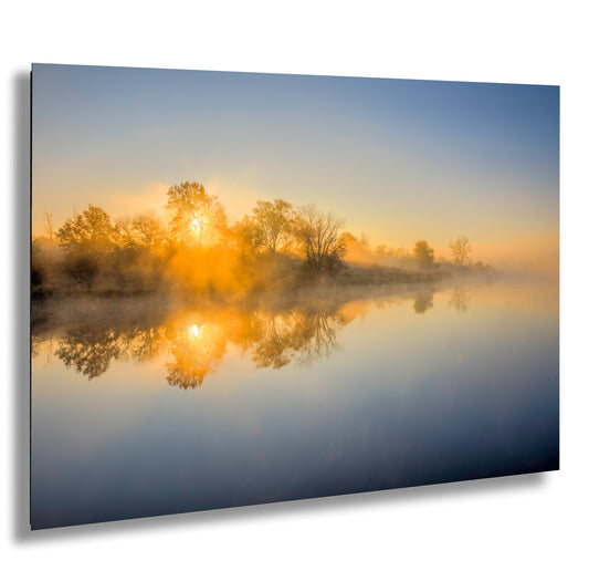 the sun is setting on a foggy lake