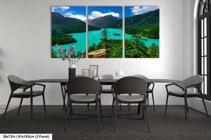 a modern dining room with a large, three-panel landscape painting depicting a scenic mountain lake surrounded by lush forests. The painting is hung on the wall above a black dining table with six chairs. The room has a minimalist and contemporary design, with a vase of flowers and a few decorative items on the table.
