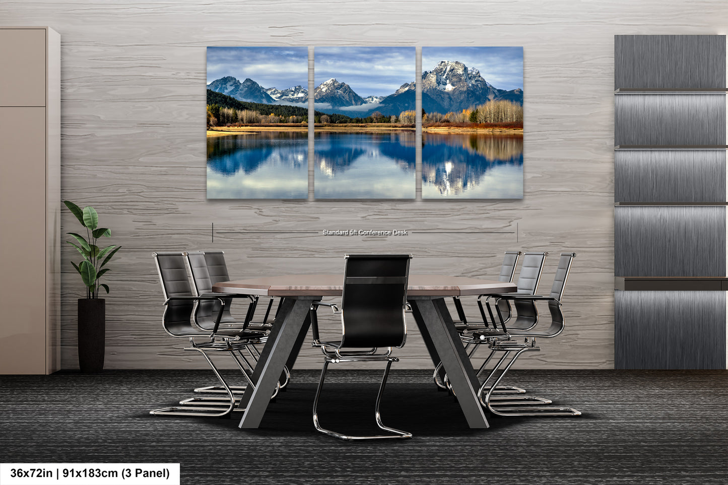 A modern office space with a large, three-panel landscape painting depicting a serene mountain lake and forest scene. The painting is mounted on a gray wall above a wooden table surrounded by black chairs.