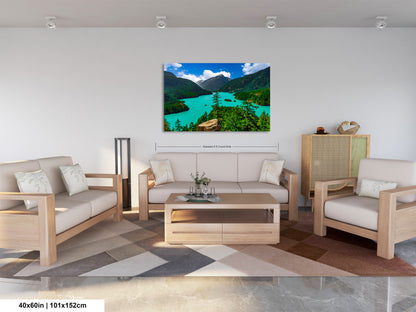 a living room with a large, colorful landscape painting hanging on the wall. The painting features a serene mountain scene with a lake and lush green trees. The room is furnished with a sofa, two armchairs, and a coffee table, creating a cozy and inviting atmosphere.