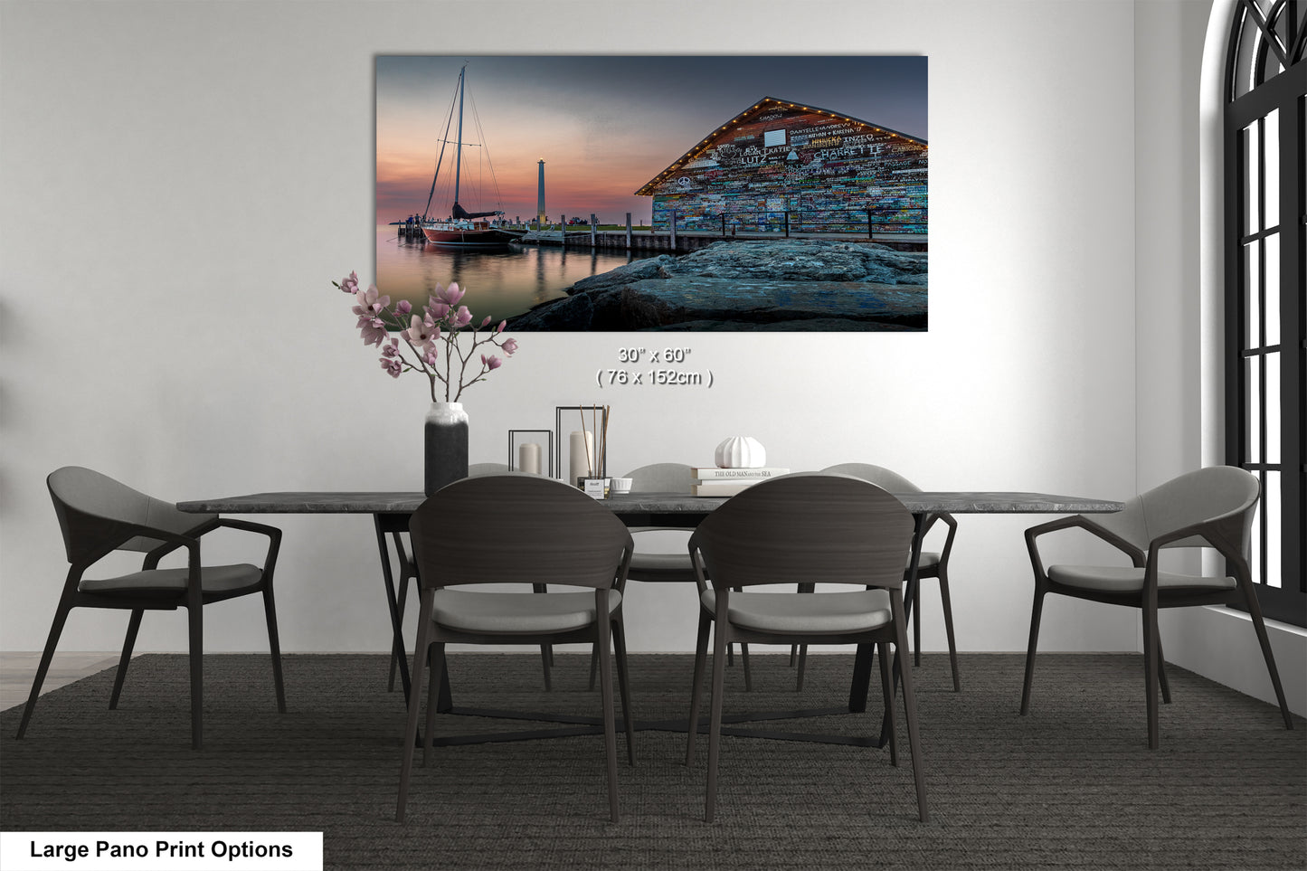 A large pano print depicting a serene harbor scene at sunset, with a wooden building and a sailboat reflected in the calm waters.
